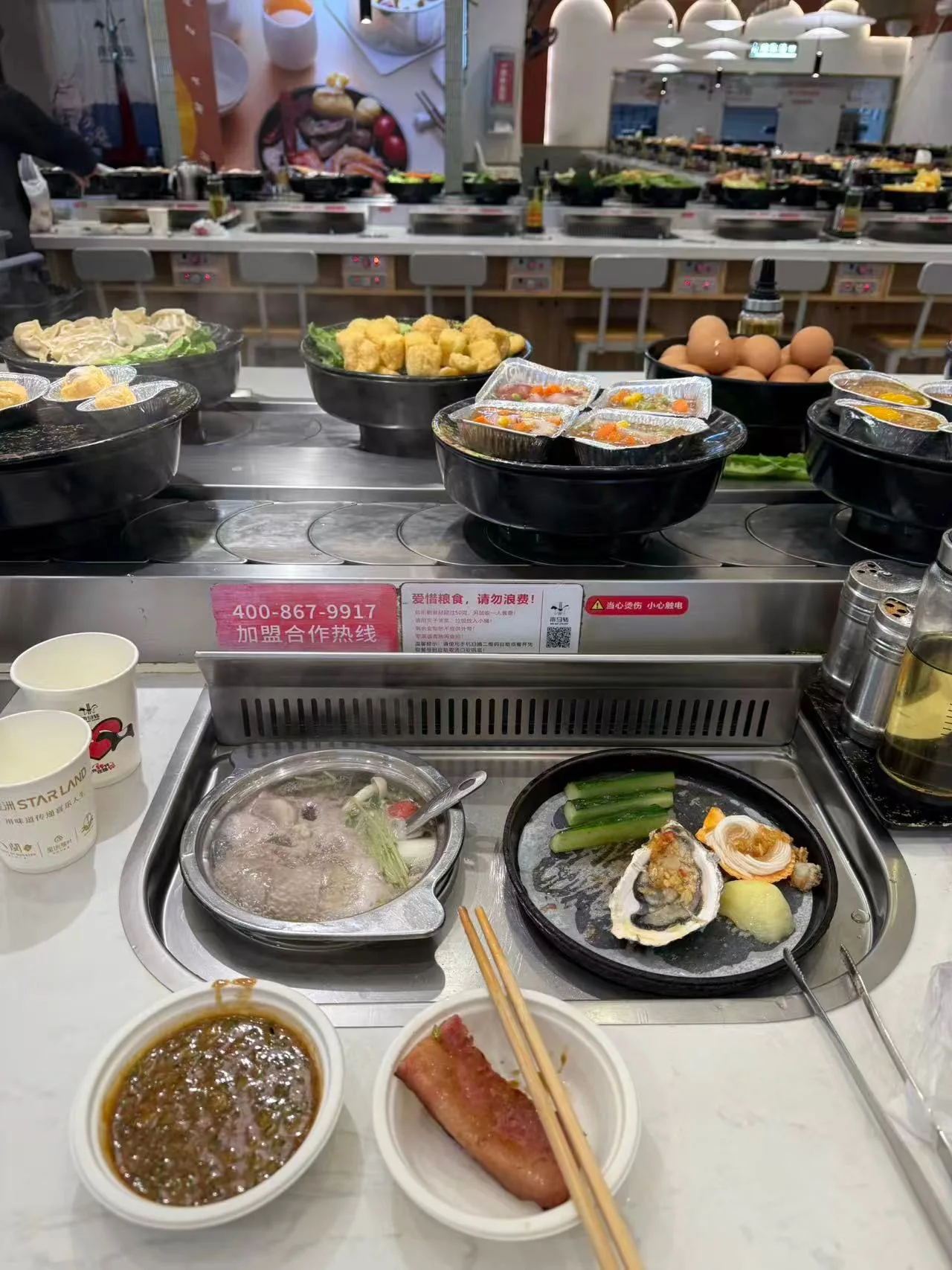 Reference image of a revolving hot pot conveyor with ingredient plates